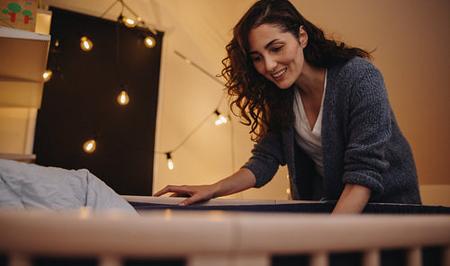 Woman adoring their baby in crib.