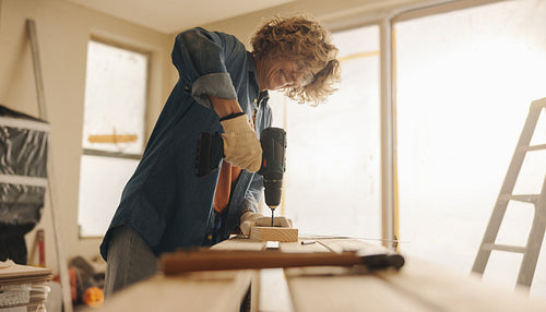 Woman smiling while renovating her kitchen with hand tools