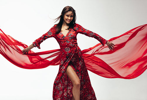 Beautiful woman in red dress with flying fabric