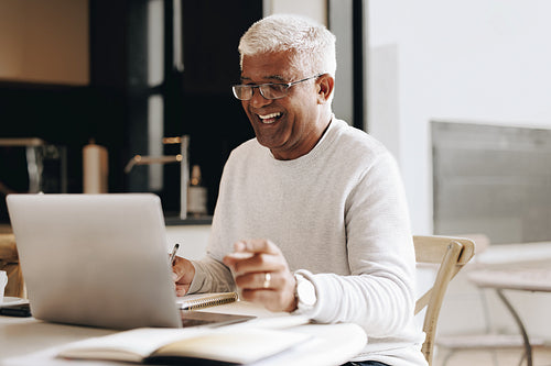 Happy senior businessman having a virtual meeting at home