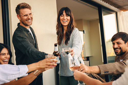 Friends toasting beverages together during a casual get-together on a home patio