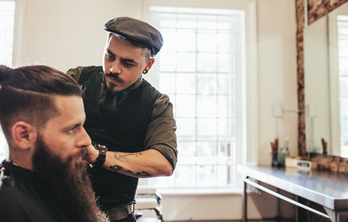 Stylish hairdresser serving client at his shop
