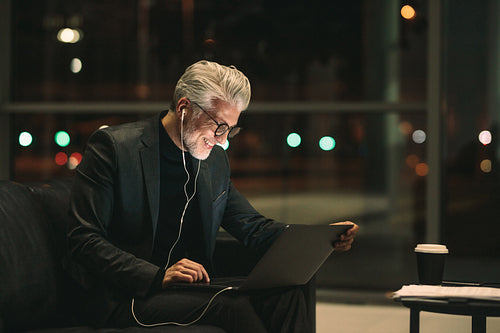 Smiling mature businessman working late on laptop