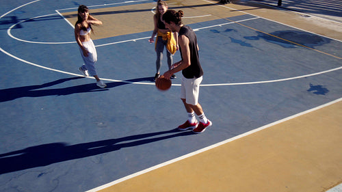 Three friends playing basketball together in a basketball court