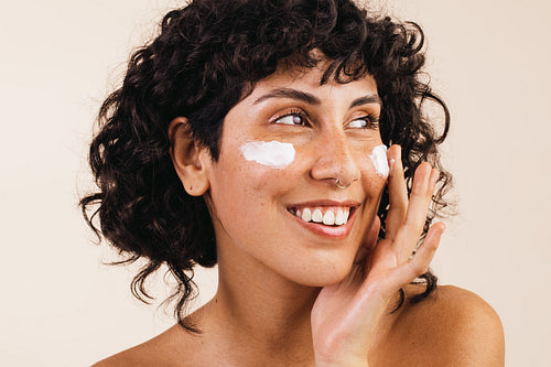 Woman applying cosmetic moisturizer on her face