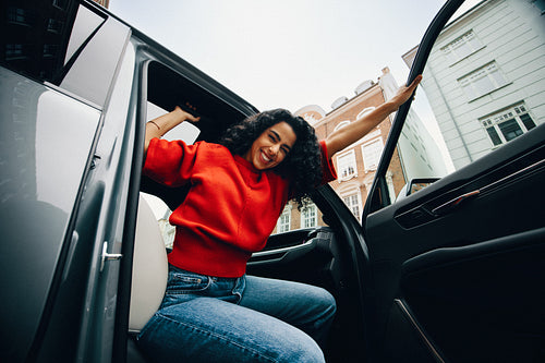 Smiling woman leaves the car in the city during her commute