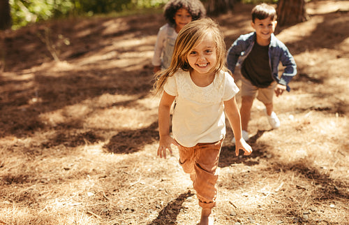 Cute girl running up hill in a park with friends