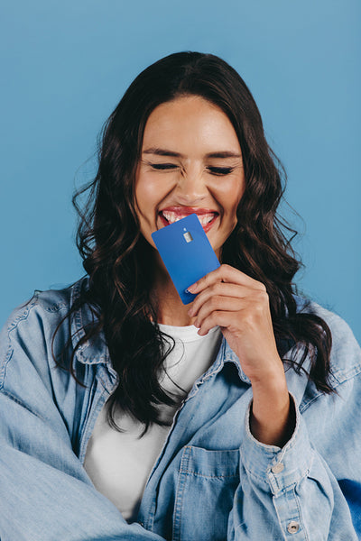 New generation of banking: Excited gen z woman holds a credit card over her chin in a studio
