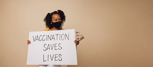 Girl holding "Vaccination saves lives" banner