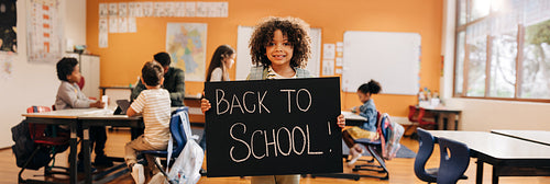 Happy boy holding a back to school sign on first day of primary education