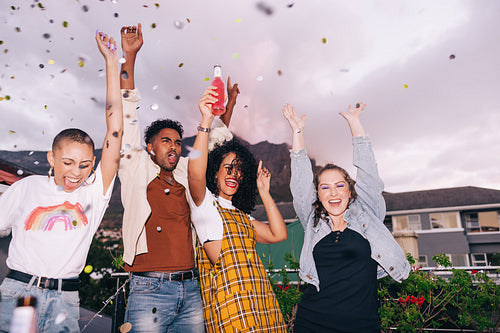 Four happy friends cheering under falling confetti