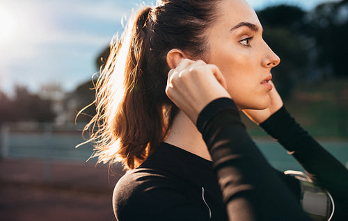 Beautiful sportswoman with earphones outdoors