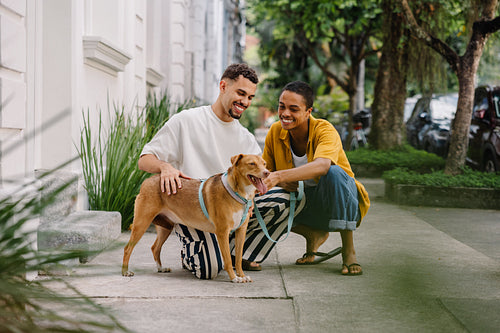 Happy couple playing with their dog on a quiet outdoor walkway