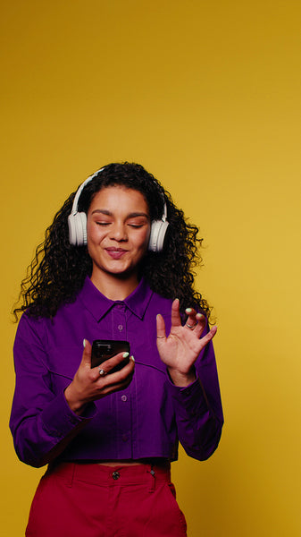 Young woman listening to music with headphones on phone and dancing