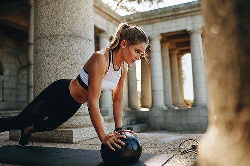 Fitness woman doing push ups using a medicine ball