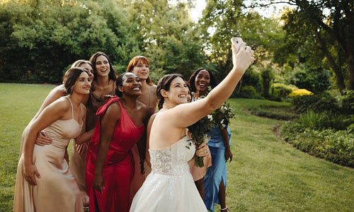 Bride and bridesmaids taking a selfie in a scenic garden setting