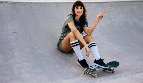 Female skateboarder with peace sign at skate park