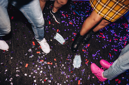 Friends stepping on confetti and face masks at a party