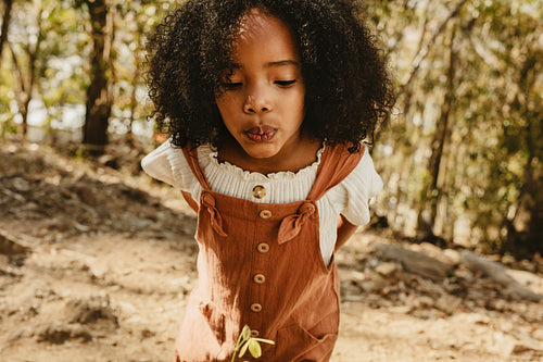 Girl blowing air on a flower in forest