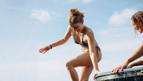 The community encourages a woman as she exits an outdoor ice bath for recovery.