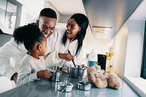 African family enjoying making breakfast together at home, couple cooking with their child