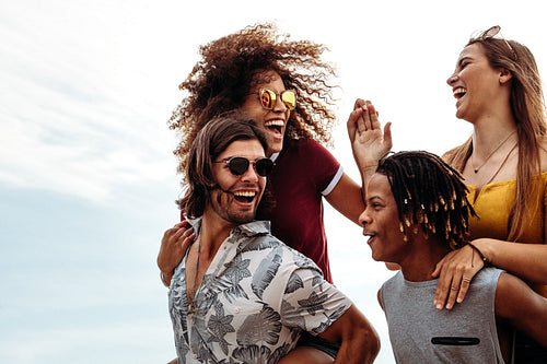 Men piggybacking girlfriends outdoors