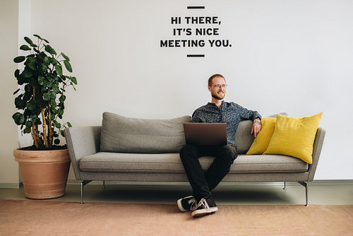 Man sitting at lobby with laptop looking away