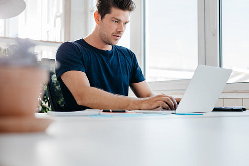 Busy young man working on laptop computer in office