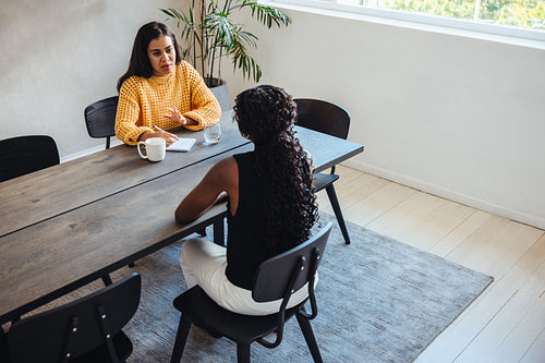 Discussion between two professional women at a modern workplace table