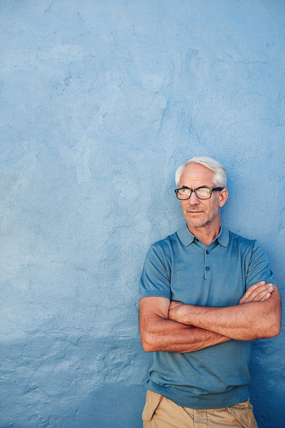 Mature man with glasses against a blue wall