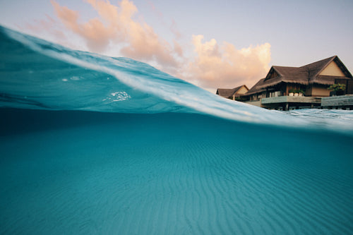 Seaside split shot view of villa with wave and turquoise water at tropical resort