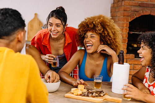 Brazilian friends laughing and drinking together at barbecue table