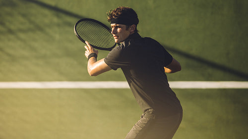 Young player playing tennis on hard court