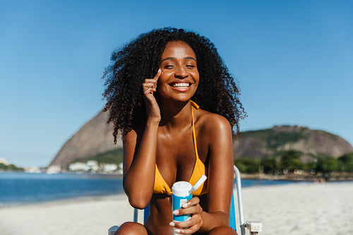 Smiling woman applying sunblock on a sunny beach in Brazil during her vacation