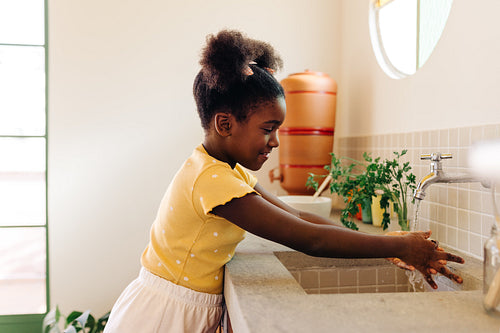 Afro-brazilian girl washing her hands with tap water