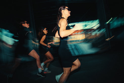 Running group of women training together in an urban run club with motion blur