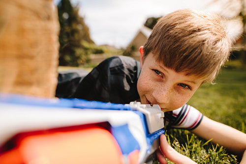 Cute boy playing with toy gun in playground