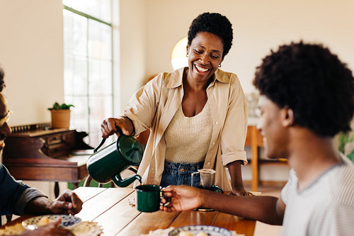 Woman serving her son Brazilian coffee during a family breakfast at home