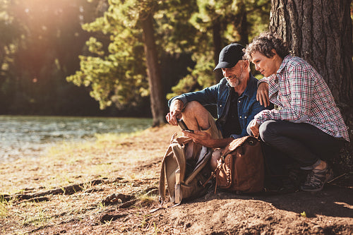 Mature couple stops to check their position while hiking