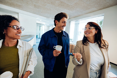 Three colleagues chat in office hallway