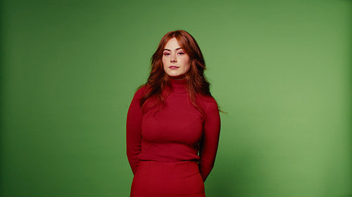 Young woman with pink makeup and red turtleneck and skirt on green screen