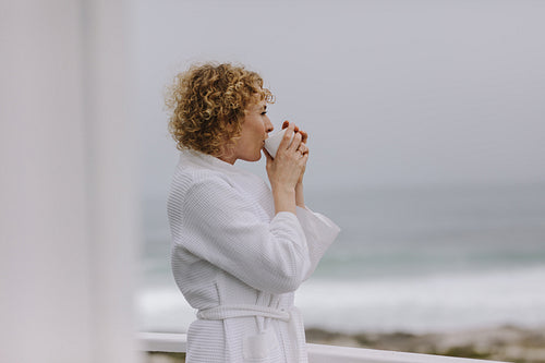 Woman relaxing at a beach house drinking coffee