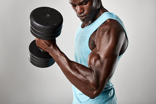 African fitness model exercising with heavy dumbbells