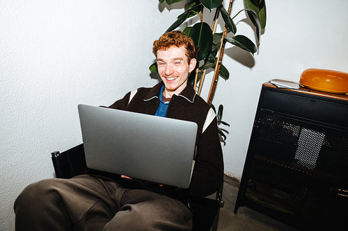 A technology-driven work scene shows a young man smiling at home.