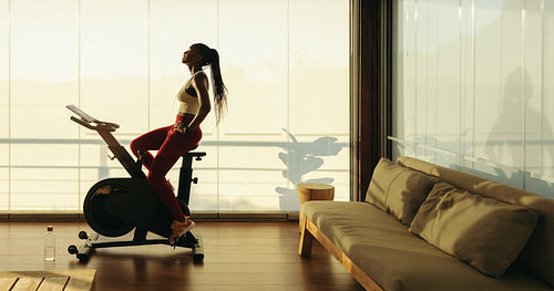 Female athlete using exercise bike in home workout routine