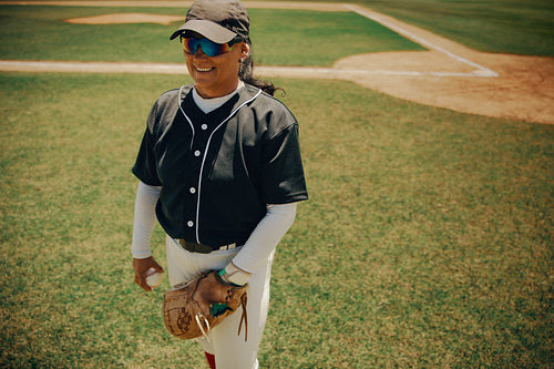 Smiling baseball pitcher wearing sunglasses on a sunny day at the field