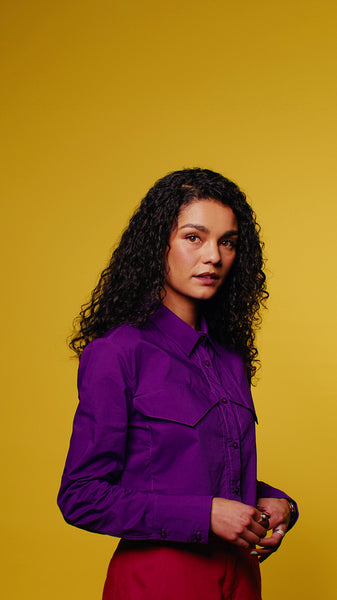 Confident young woman poses for a fashion portrait against a vibrant yellow background