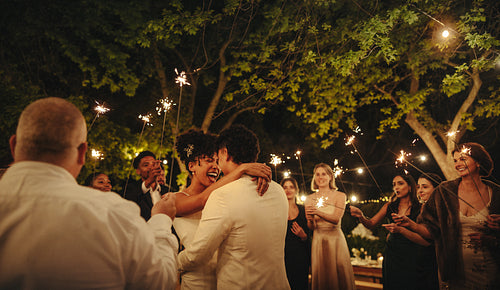 Bride and groom celebrating in a romantic outdoor wedding evening with sparklers