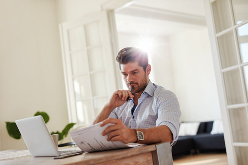 Man at home office with laptop and reading documents