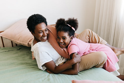 Mom and daughter smiling after a pillow fight